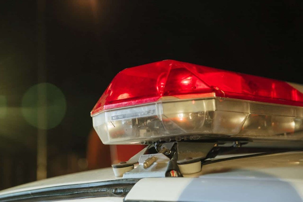 Sirene vermelha acesa no teto de uma viatura policial à noite