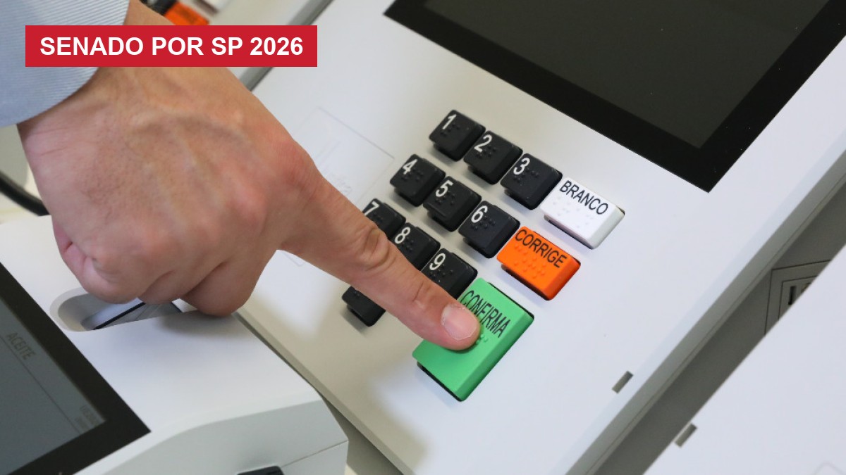 Dedo de eleitor sobre a tecla verde CONFIRMA de uma urna eletrônica brasileira